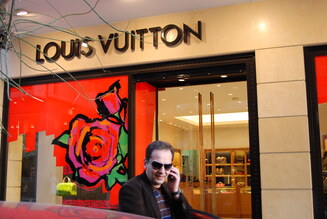 A man talking on his cell phone outside of a Louis Vuitton store