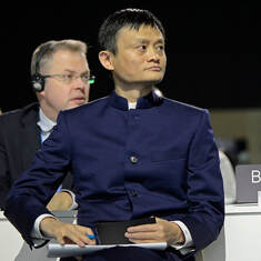 Jack Ma listening with an ink pin in hand and paper on his lap