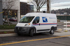 A mail van parked on a side street outside of a building