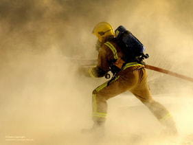 A firefighter holding an active waterhose 