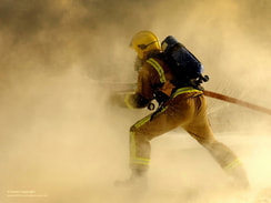 A firefighter holding an active water hose