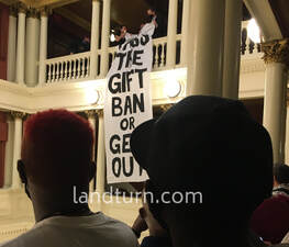 Protesters unfold a banner longer than 20 feet that in part reads, 