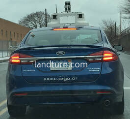 A self-driving car seen in front of my car with what might be a GPS console on the hood