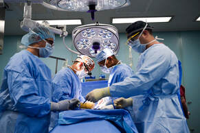 Health care professionals standing over a patient in surgery